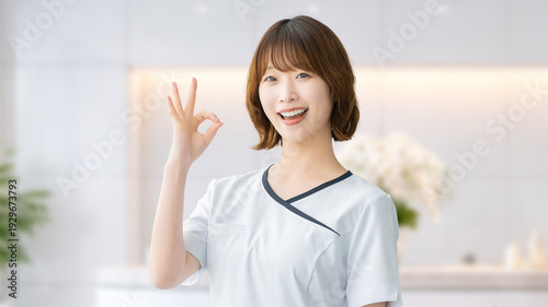 Photos 美容サロンでOKサインをする笑顔の女性スタッフ,清潔感のあるエステイメージ, Smiling Female Staff Showing OK Sign at a