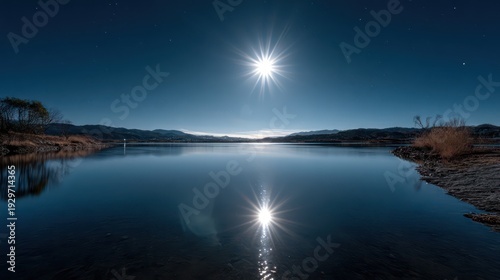 Brilliant full moon illuminates still water surface reflecting celestial light across a dark landscape.