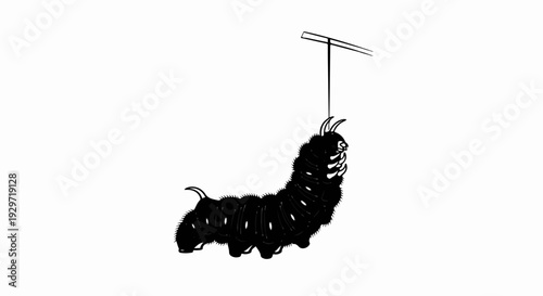 A fuzzy black caterpillar hangs from a thin line attached to a T-shaped bar