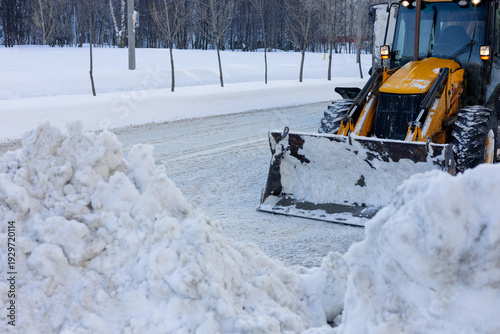 A snowplow on the road. A tractor clears the road of snow. Snowy winter, blizzards.