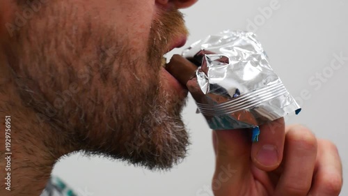 Close-up of a chocolate bar in the hand of a man biting it