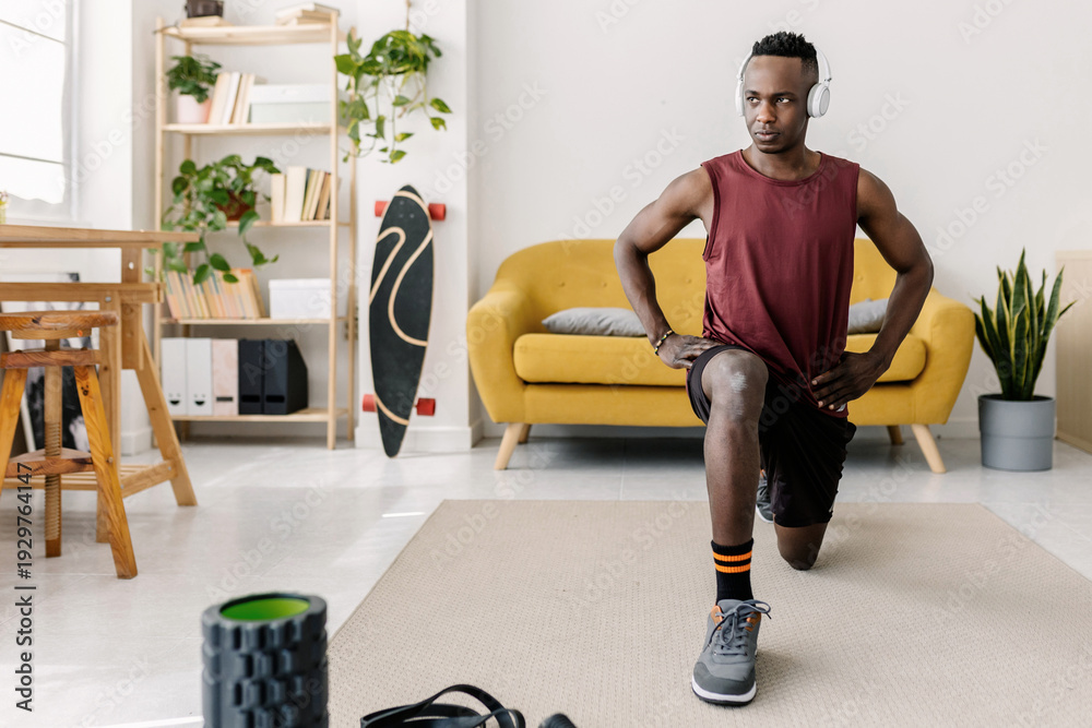 Fototapeta premium Young adult black man performing lunges in living room, using exercise equipment for fitness and healthy lifestyle. Fitness concept