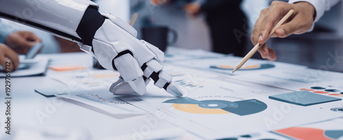 Foto A futuristic scene of a robotic hand assisting a human in analyzing colorful charts and graphs on a table, representing the collaboration between technology and human effort