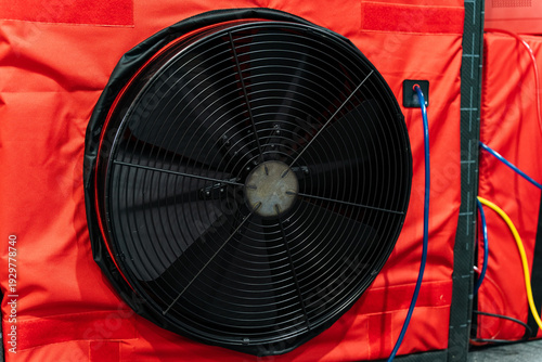 Red Industrial Fan. Heavyduty Air Leakage Tester Device. Large Crimsonframed Machine With Metal Blades And Wiring. Vivid Red Casing Around Sizable Black Metalbladed Air Flow Tester