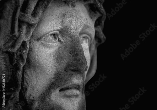 Dramatic black and white close-up of Jesus Christ stone statue with intense upward gaze, symbol of faith, sacrifice, and spiritual strength.