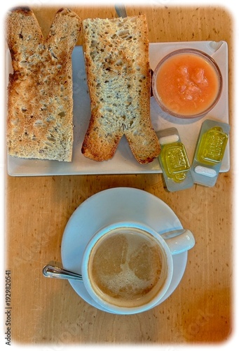 Traditional Spanish breakfast with toast, fresh tomato, olive oil and coffee with milk on a wooden table