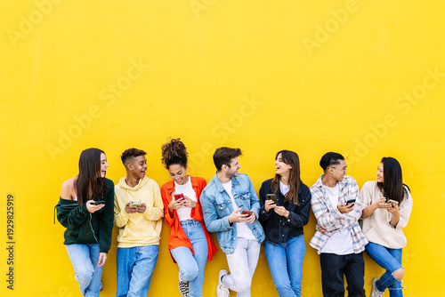 Multiracial young friends having fun sharing media content on mobile phone. Communication and social media concept