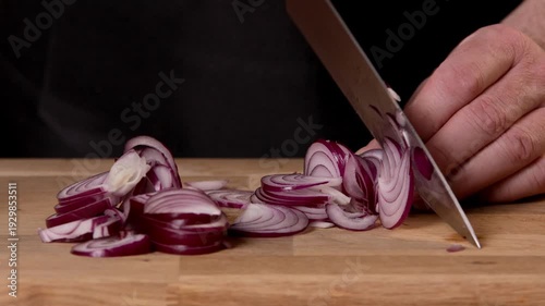 A chef cuts onions for a salad on a cutting board