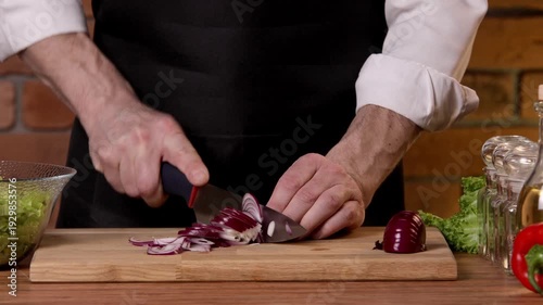 A chef cuts onions for a salad on a cutting board