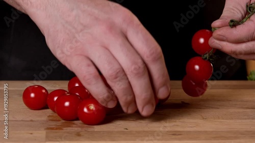 The cook picks tomatoes from the vine to cut them for the salad.