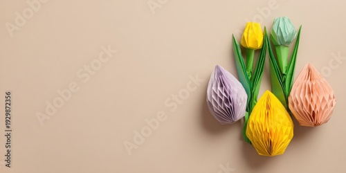 Colorful paper tulip flowers arranged on beige background with copy space, creative spring and Easter decoration concept.