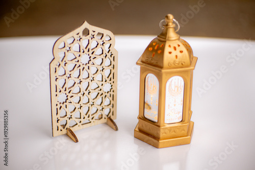 Elegant Islamic wooden geometric ornament and golden Arabic lantern on a white table. Minimalist Ramadan and Eid decorative concept