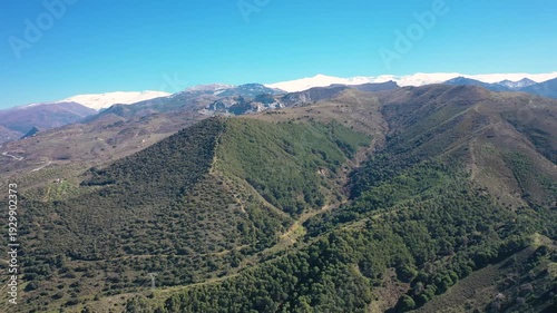 Aerial 4K video from a drone of the snow-capped mountains of the Sierra Nevada on a sunny day. In the background, the green mountains of Granada. Sierra Nevada, Granada, Andalusia, Spain.
