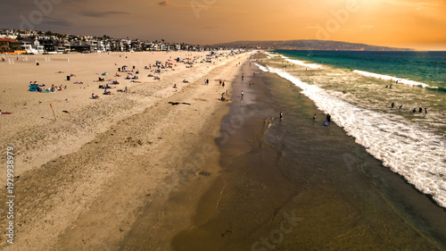 Sunset Aerial View of a Crowded California Beach with Breaking Waves and Coastal Homes