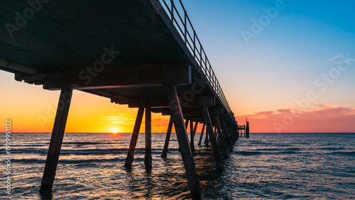 Schilderij op canvas Dramatic sunset at Glenelg Beach with jetty silhouette and glowing horizon, Adel
