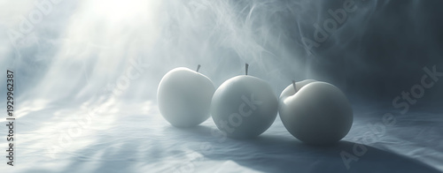 Radiant light dramatically highlights three minimalist fruits, emerging from a gentle mist, creating a captivating and otherworldly still life composition