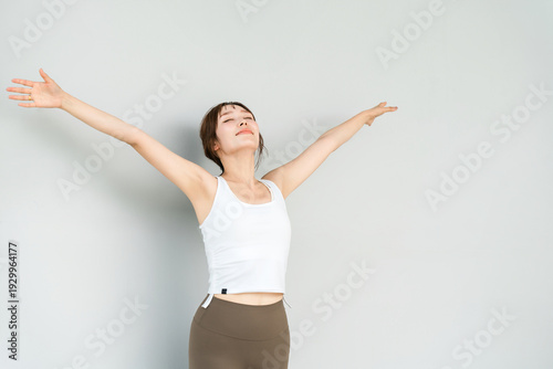 Tableau sur toile A woman wearing yoga wear and sportswear stretching, taking deep breaths and ref