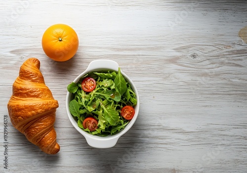 Delectable brunch composition with croissant, salad, and orange fruit