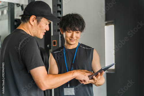 Tapety artystyczne パーソナルジムで会員に個別指導するトレーナーの男性