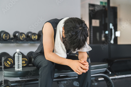 Tableau sur toile Training gym, young asian man taking a break at sports gym