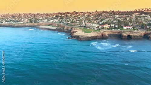 Aerial panorama of San Diego County coastline with cliffs, waves and upscale coastal neighborhood homes