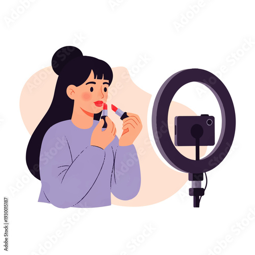 A young woman applies lipstick while recording herself with a smartphone and ring light
