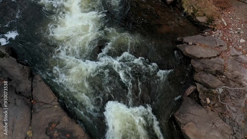 Overhead drone view of the white rapids between the rocks and moving slowly forward