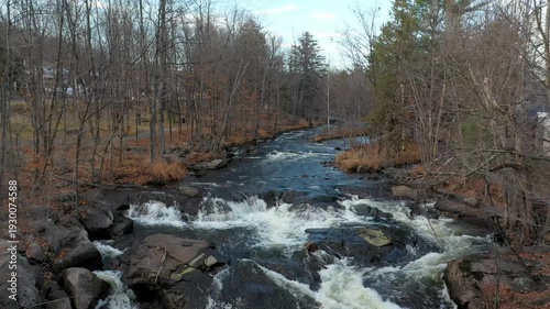 Flying backward in mid-air, revealing the beautiful scenery of Fall, over the river and the small rapids.