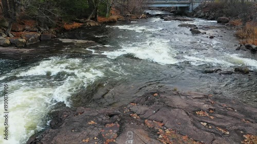 Mid-air flight with a drone showing the rapids of the river, in the village with the surrounding of the colors of the Fall.