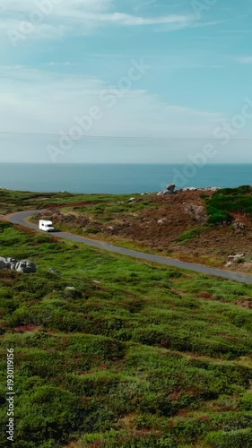 White camper van driving on a scenic coastal road. Media