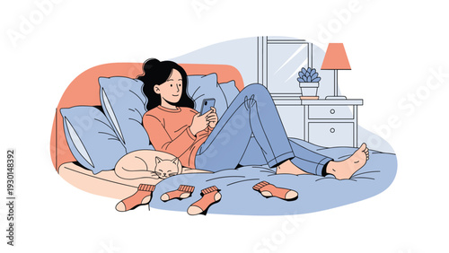 Young woman lies on her bed using a smartphone with several pairs of socks scattered around her and her cat nearby in the bedroom.