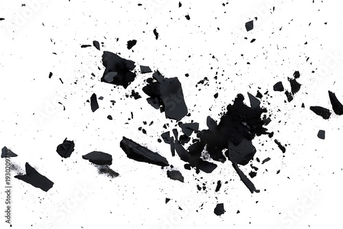 Black fragments and particles scattered on a plain white surface  broken pieces and dust