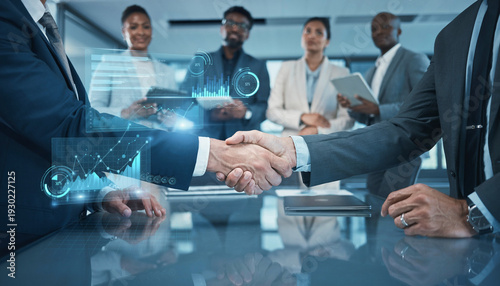 Diverse business team shaking hands with holographic charts showing growth, symbolizing success and partnership in modern corporate environment.