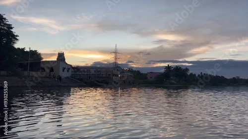 A calm evening settles near the temple water pond as the sky turns soft orange and pink. Gentle ripples reflect the fading light, and the peaceful silence creates a divine and soothing atmosphere. 🌅