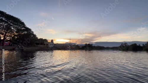 A calm evening settles near the temple water pond as the sky turns soft orange and pink. Gentle ripples reflect the fading light, and the peaceful silence creates a divine and soothing atmosphere. 🌅