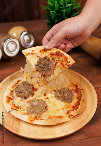 Small homemade frozen pizza toppings hamburge minced pork patties stretching melty cheese golden yellow color on wooden board tasty food fresh delicious cuisine gourmet italian style thin crust.