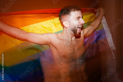 Shirtless man celebrating identity holding pride flag