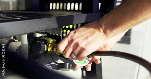 Hands of man attaching black gas hose to propane tank - steady cam