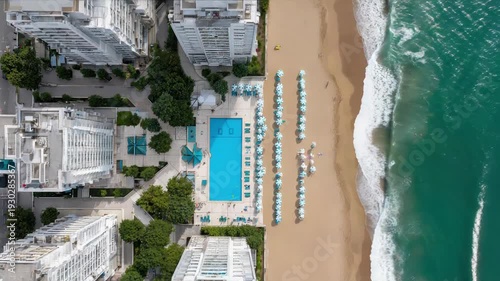 Aerial view of coastal city with beachfront hotels and turquoise ocean waves