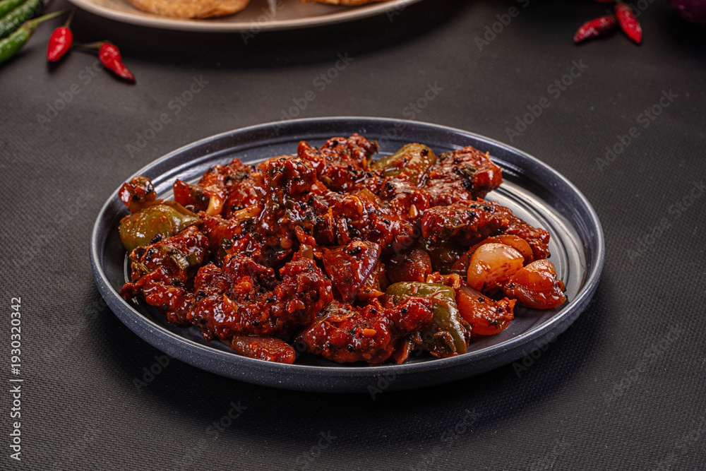 Fototapeta premium Spicy Indian chili dish with peppers and onions served on a gray plate