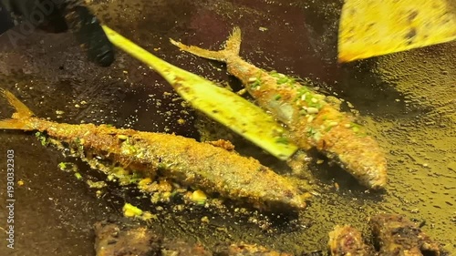 Delicious fish cooking in hot oil with herbs