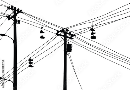 Silhouette of utility poles with insulators, crisscrossing power lines, rural electricity distribution, energy infrastructure, industrial landscape, high voltage electrical grid