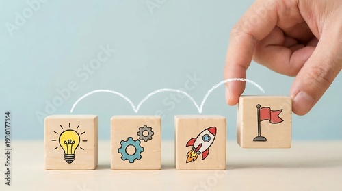 Wallpaper Mural A person's hand places a final wooden block featuring a red flag goal at the end of a sequence showing idea, process, and launch icons. Torontodigital.ca