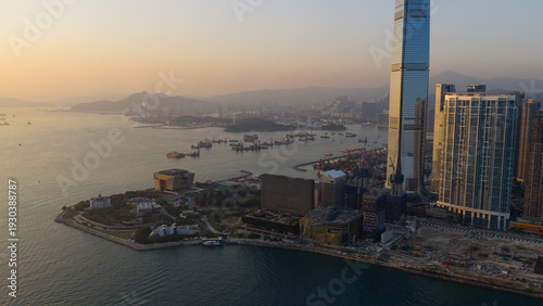 Hong Kong, Hong Kong - 13 February 2026: Aerial view of a sprawling cityscape where the iconic International Commerce Centre pierces the hazy sky, contrasting with the muted tones of the harbor below.