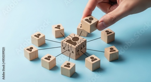 A hand strategically connecting wooden blocks in a network formation