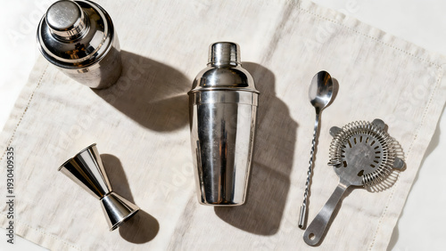 Cocktail Essentials: An overhead shot showcases essential stainless steel bar tools arranged on a textured cloth, perfect for crafting elegant drinks.