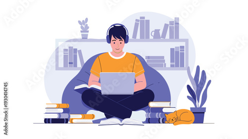 Young student sits on a comfortable beanbag chair using his laptop and listening to music while surrounded by books.