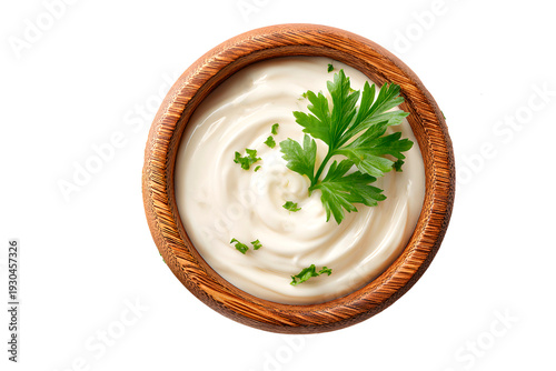 Top view of wooden bowl with creamy mayonnaise and parsley garnish, isolated on white background.