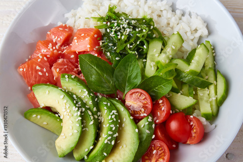 Fotografie Poke bowl with salmon, rice, avocado, cucumber, mango, micro green and carrot