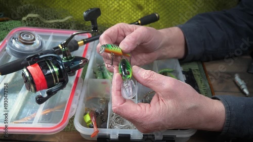 Wallpaper Mural Sport fishing equipment on a table in a studio composition, against a background of a net. A fisherman's hands check the tackle for use. Torontodigital.ca